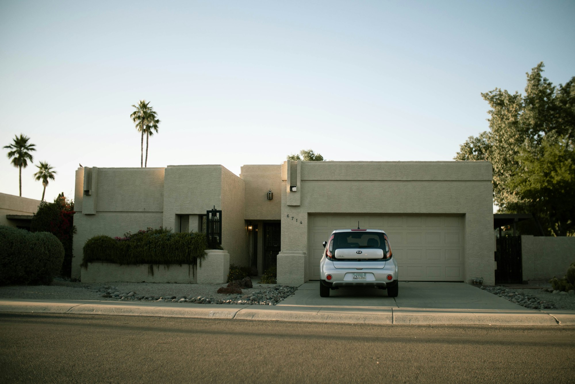 Stucco home with palm trees and a car in the driveway Stucco home with palm trees and a car in the driveway