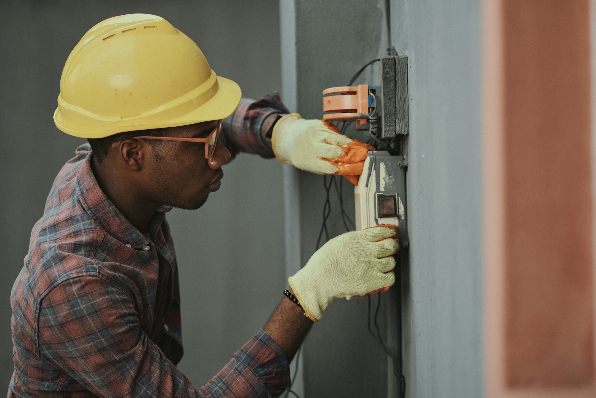 Electrician in a hard hat installing wiring Electrician in a hard hat installing wiring