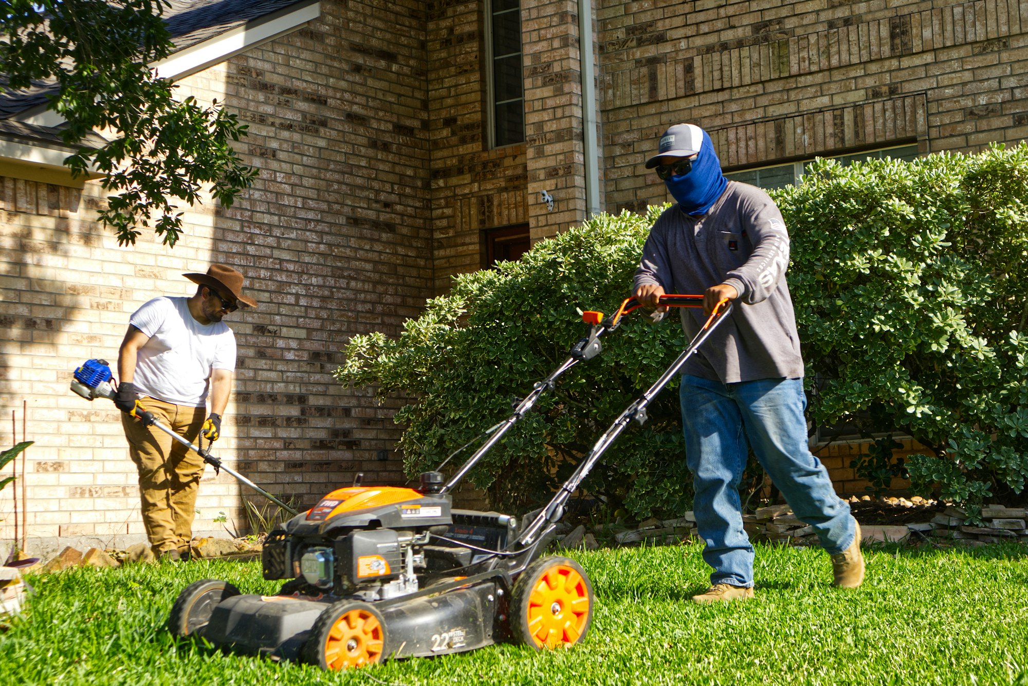Landscaping crew mowing and trimming a residential lawn Landscaping crew mowing and trimming a residential lawn