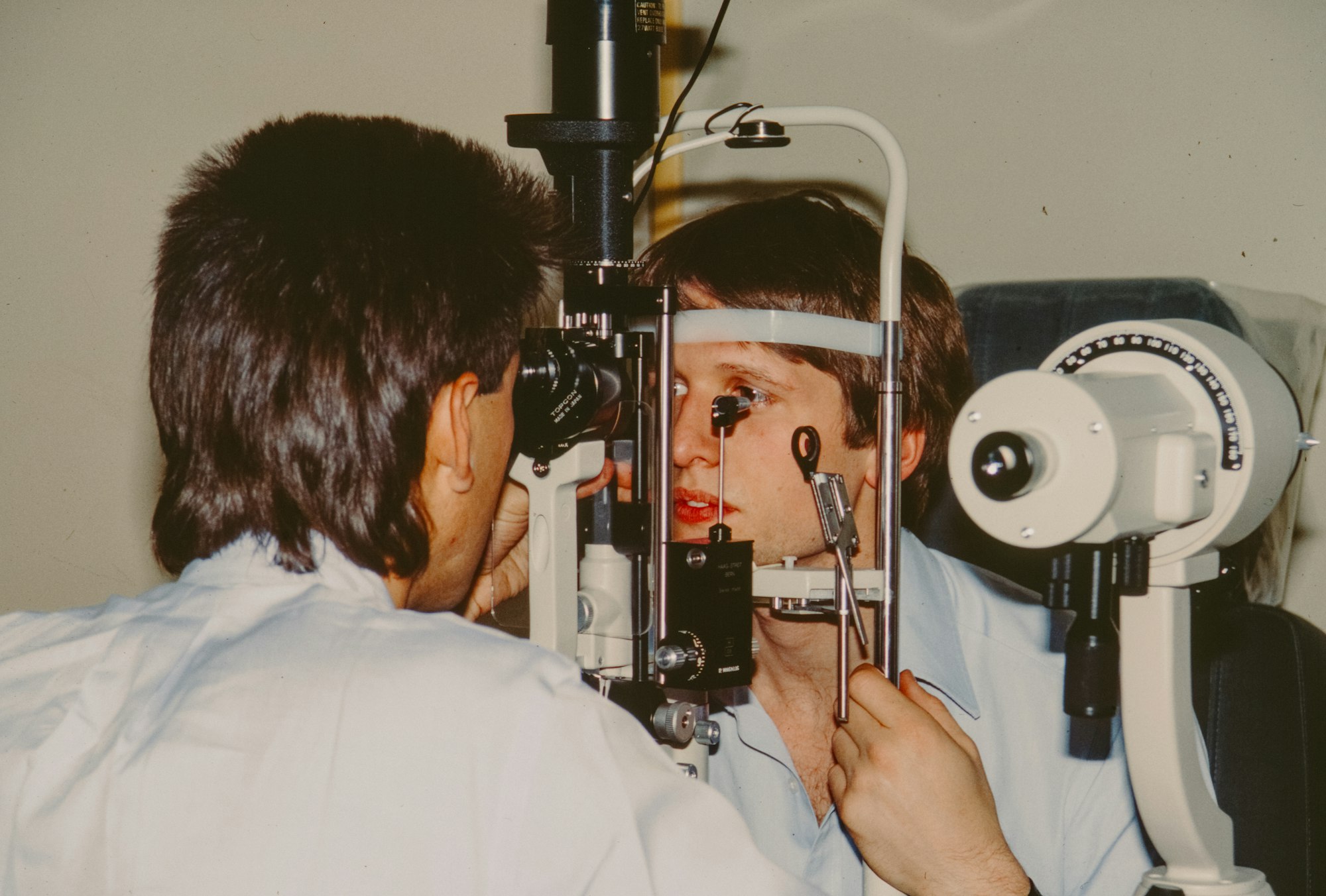 Optometrist examining a patient’s eyes with a slit lamp Optometrist examining a patient's eyes with a slit lamp