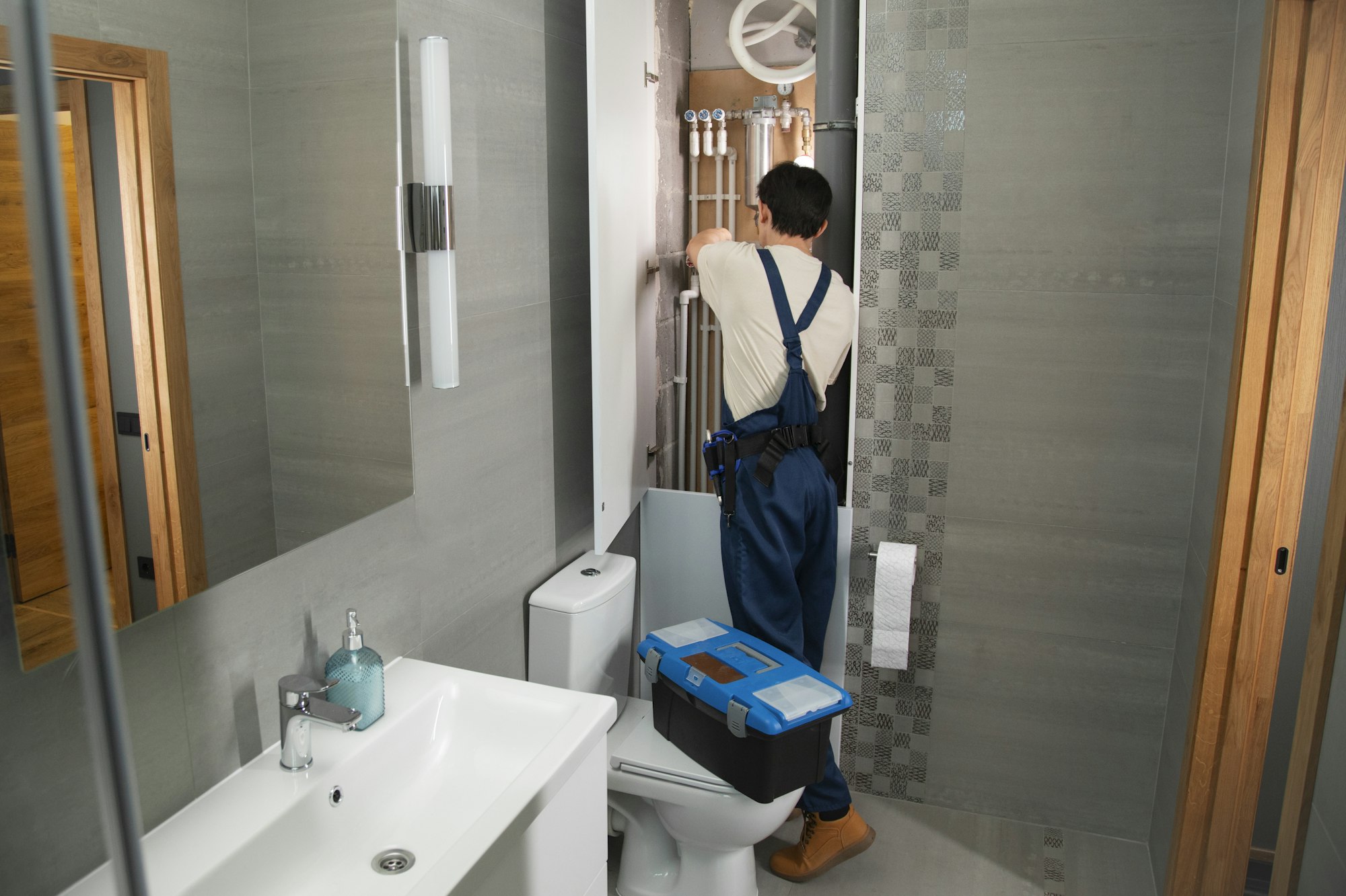 Plumber with a toolbox working in a bathroom Plumber with a toolbox working in a bathroom