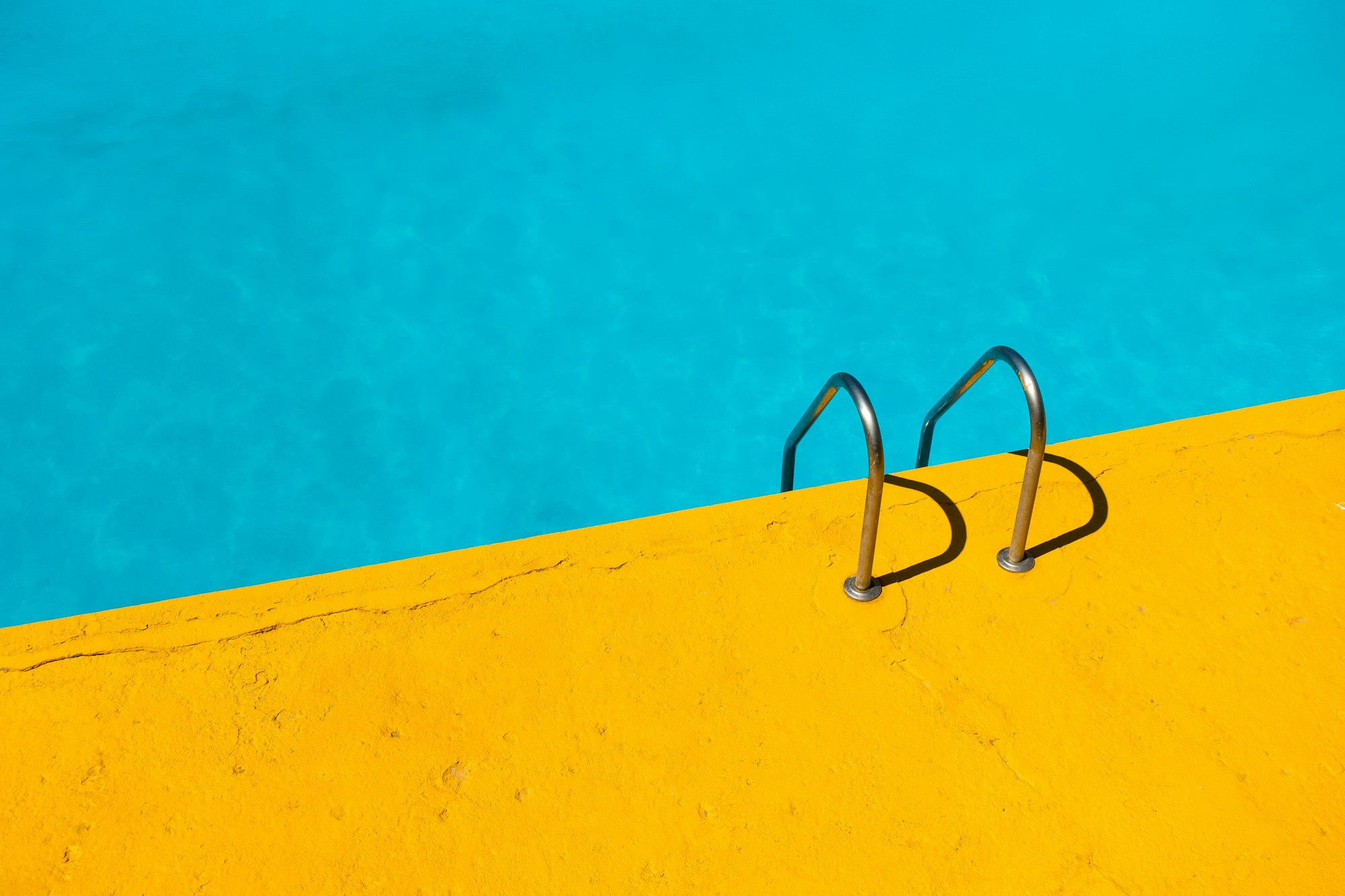 Pool ladder on a yellow pool deck Pool ladder on a yellow pool deck
