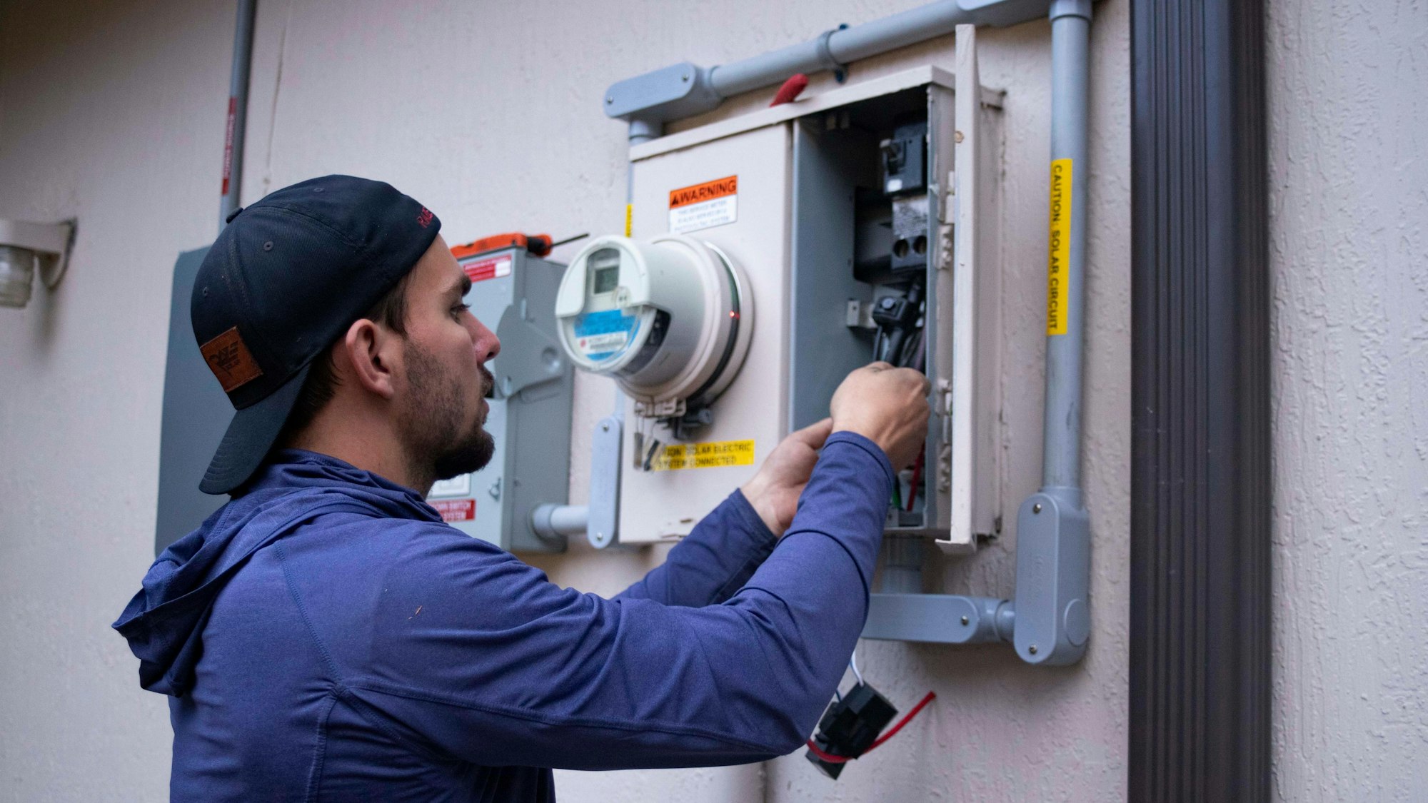 Technician working on an electrical meter panel Technician working on an electrical meter panel